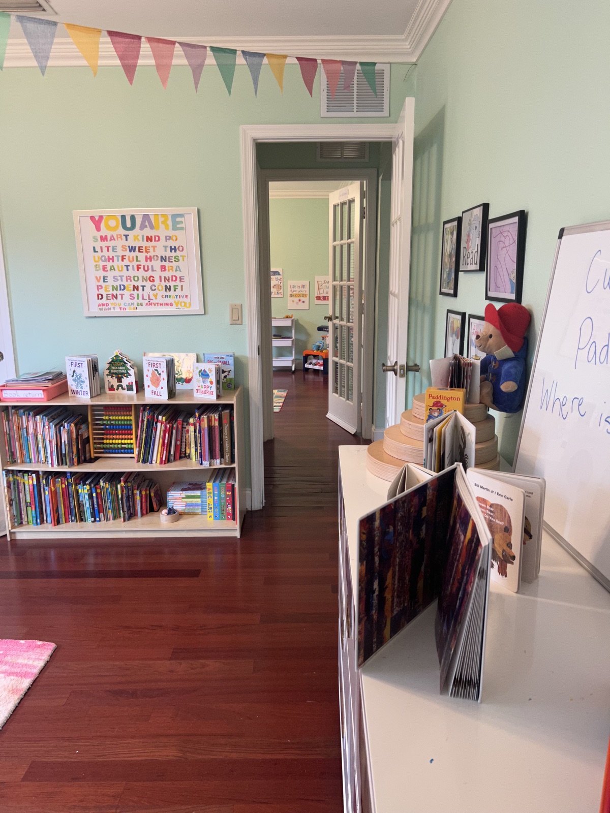 A children's library nook with bookshelves, board books, and a colorful pennant banner